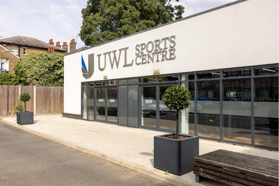 Exterior view of the UWL Sports Centre building with large windows, potted trees, and clear signage.