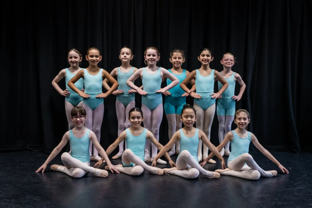 young ballet students posing together in teal leotards during dance class recital
