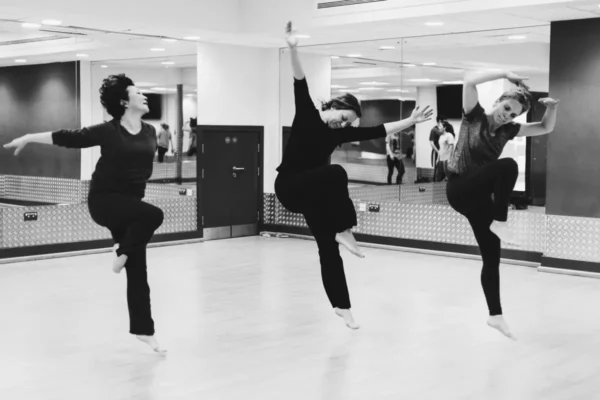Three adult dancers in black dancewear holding a pose in the SA Dance studio