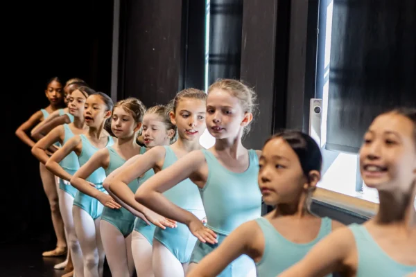 Line of Junior dancers in aqua SA Dance leotards working along the barre in the studio