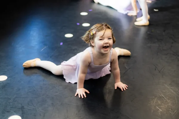 Young Tiny dancer smiling while sitting on the studio floor