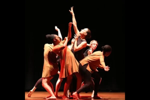 Group of adult SA Dance dancers in rust and orange costumes performing together on stage